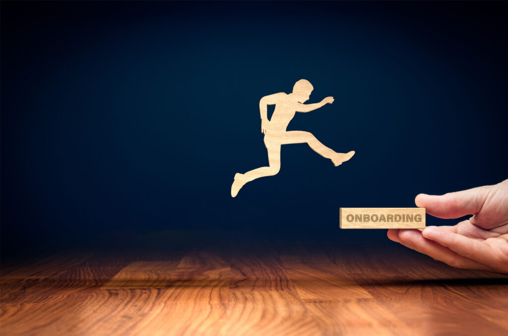 Wooden silhouette of a man jumping onto a block with the word 'Onboarding' stamped on it.