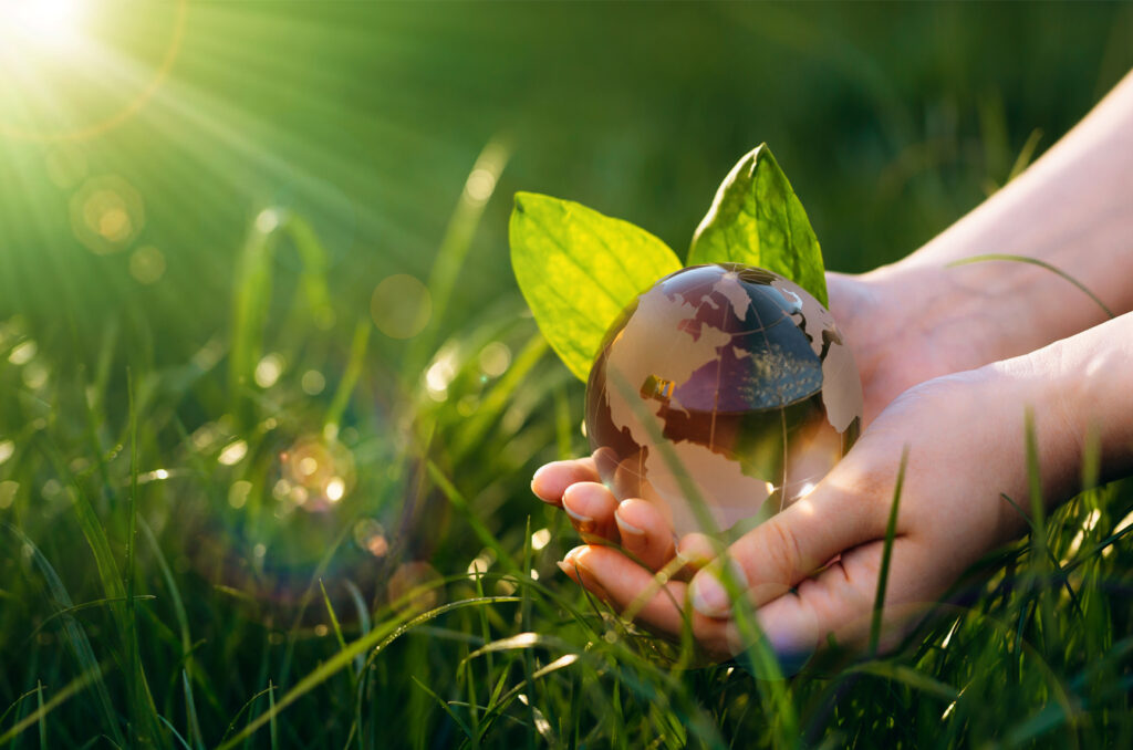 Hand holding a crystal earth globe symbolizing sustainability concept.